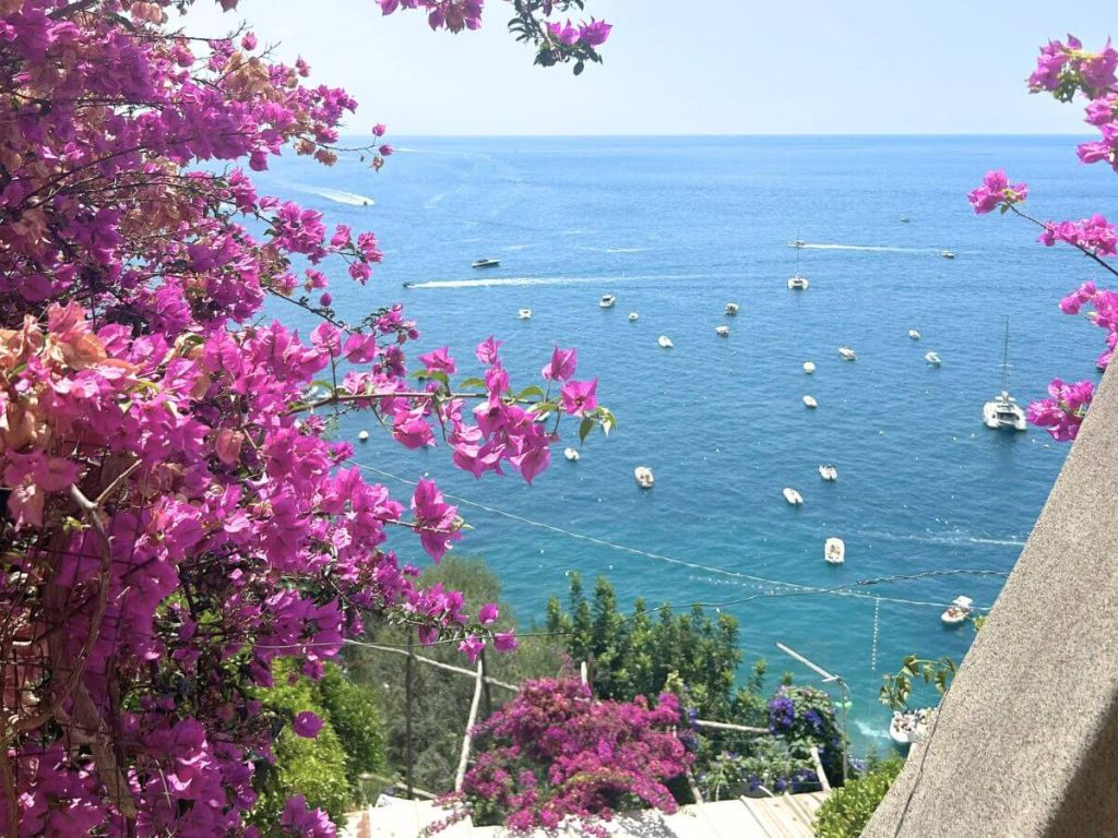 View of beautiful turquoise sea and pink flowers on Amalfi Coast honeymoon