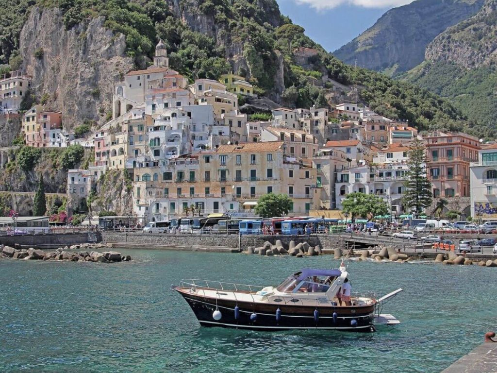 Boat in the sea on the Amalfi Coast with pastel buildings in background